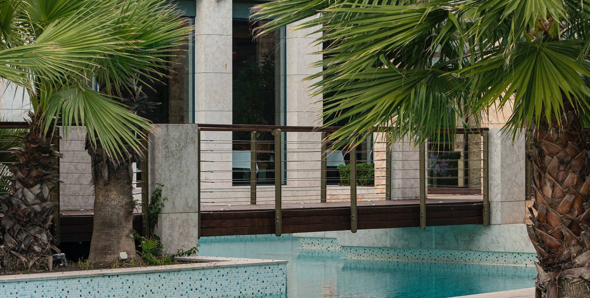 A pool area with a deck and palm trees in front of a building